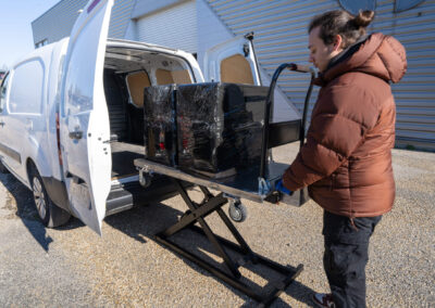 Un homme utilise le chariot AKTA ROLLIFT pour charger des cartons dans un véhicule utilitaire.